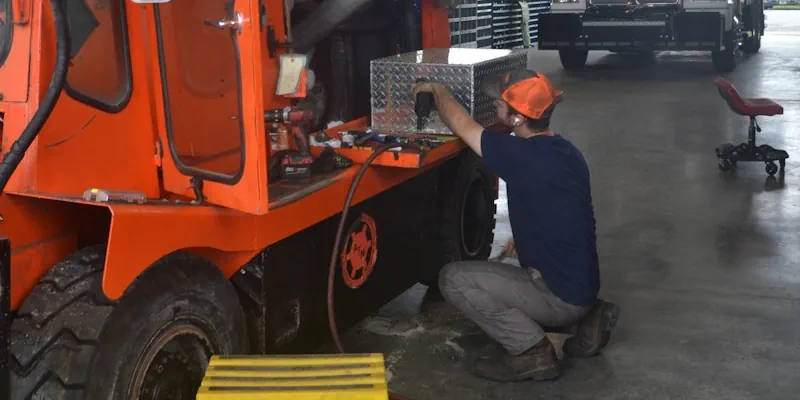 young man working on orange truck inside shop